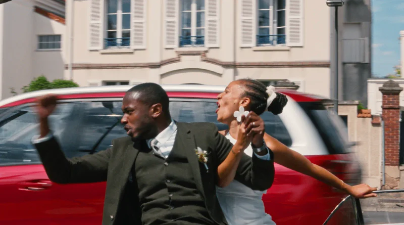 Una novia y un hombre trajeado bailan y cantan enérgicamente en la calle delante de un coche rojo en la película Dao.
