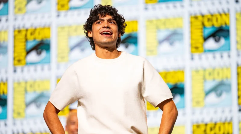Primer plano del actor Iñaki Godoy, protagonista de One Piece, sonriendo abiertamente y de pie sobre el escenario del evento.