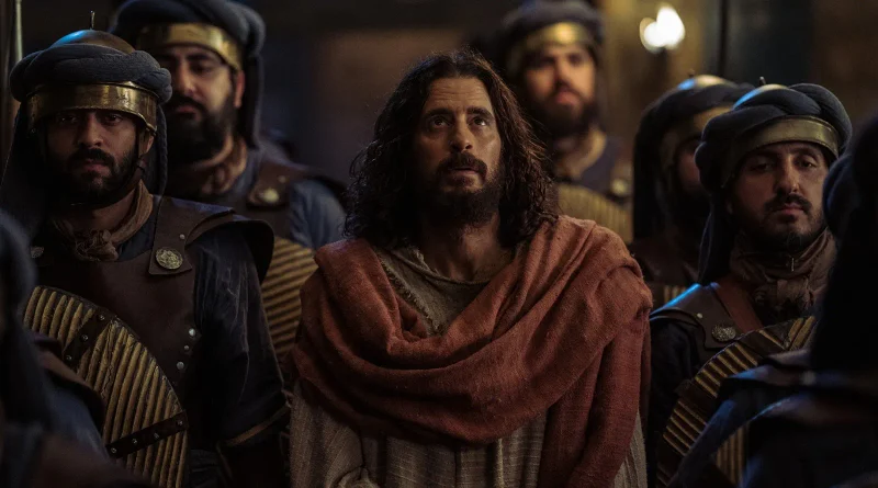 Jesús mira fijamente hacia el cielo con expresión de resignación mientras está fuertemente custodiado por guardias en la serie The Chosen.
